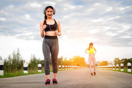 Runners - two women running outdoors training. Exercising female athletes jogging outside on nature...