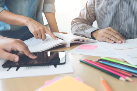 Education, teaching, learning, technology and people concept. Group of high school students or classmates with helps friend catching up workbook learning in classroom, Tutor books with friends.の写真素材