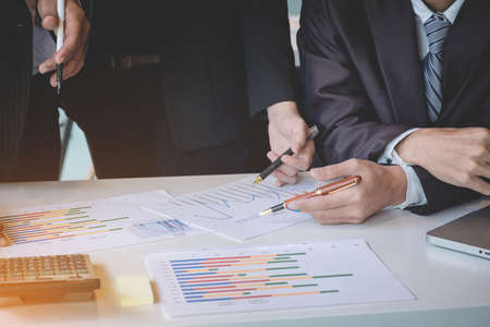Business team colleagues discussing new plan financial graph data on office table with laptop and digital tablet.の写真素材