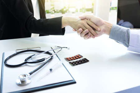 Male doctor in white coat shaking hand to female patient after successful treatment.の写真素材