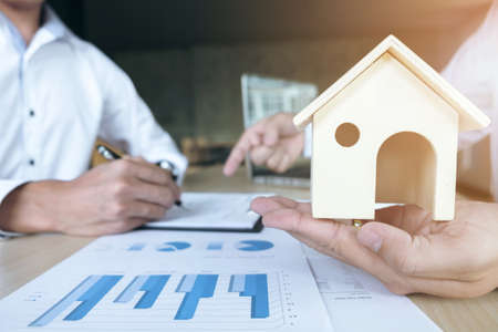 Man sign a home insurance policy on home loans, Agent holds home and pointing loan documents. Real Estate concept.の写真素材