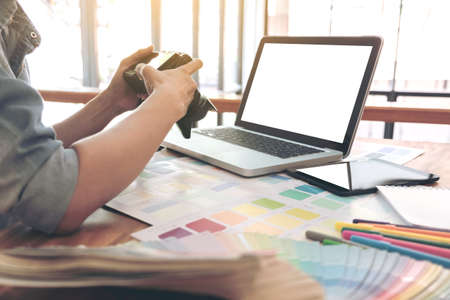 Color samples, colour chart, swatch sample, Graphic designer being selecting Color band and graphics tablet at workplace with work example in camera and laptop on wooden desk.の写真素材