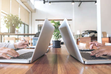 Two business persons working at office desk and discussing using laptop to ideas of project about...