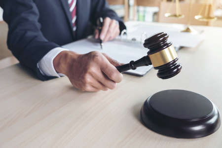 Close up of gavel, Male lawyer working with scales of justice, books, report the case on wooden table in office, Law and justice concept.の写真素材