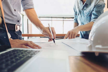 Image of engineer or architectural project, two engineering discussing and working on blueprint with...