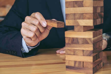 Alternative risk concept, plan and strategy in business, Risk To Make Buiness Growth Concept With Wooden Blocks, Images of hand of businesspeople placing and pulling wood block on the tower.の写真素材