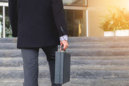 Businessman walking up the stairs and holding a briefcase in hand working with confidence.の写真素材