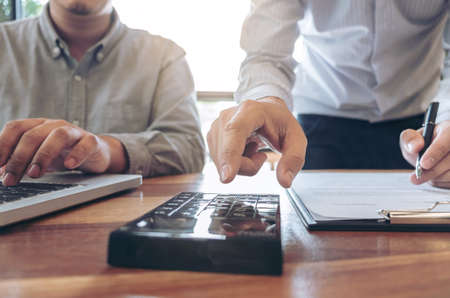 Two confident executives business colleagues meeting and discussing ideas of project about company offer, they is pointing on a contract and giving explanations, team of successful business people.の写真素材