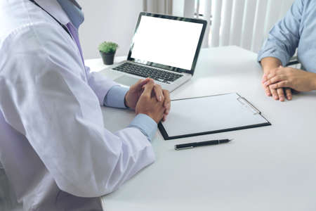 Close up of doctor filling up an history form while consulting patient and recommend treatment methods and how to rehabilitate the body.の写真素材