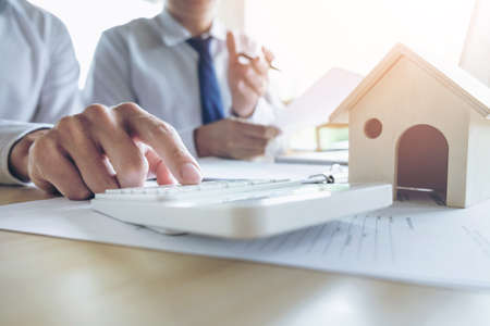 Man sign a home insurance policy on home loans, Agent holds loan investment chart graph documents and calculating table installment payment, Real Estate concept.の写真素材
