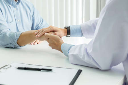 Close up of doctor touching patient hand for encouragement and empathy on the hospital, cheering and support patient, Bad news, medical examination, trust and ethicsの写真素材