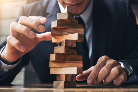 Alternative risk concept, plan and strategy in business, Risk To Make Buiness Growth Concept With Wooden Blocks, Images of hand of businesspeople placing and pulling wood block on the tower.の写真素材