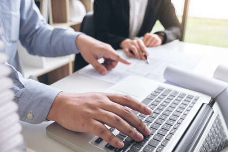 Engineering or Creative architect in construction project, Engineers hands working on construction blueprint and building model at a workplace in office, Building and architecture concept.の写真素材