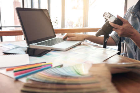 Color samples, color swatch samples, Draw architecture, Graphic designer selecting on colour chart, pens at workplace with work example in camera and laptop on wooden desk.の写真素材