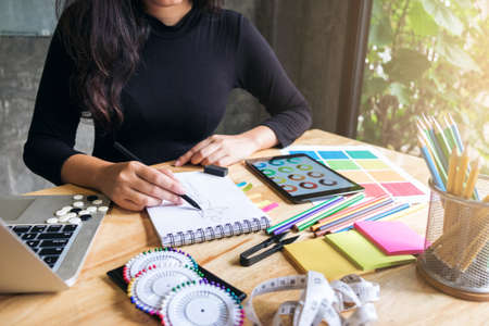 Young woman dressmaker or designer working as fashion designers and drawing sketches for clothes profession and job occupation, Fashion Designer Stylish Concept.の写真素材