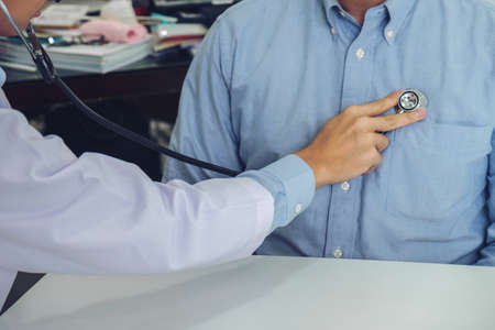 Close up of doctor listening to patient heartbeat with stethoscope on hospital, Physical examination, Medical and health care concept.の写真素材