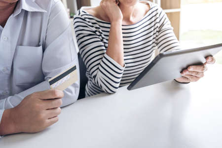 Two people using tablet and credit/debit card register payments online shopping and customer service...