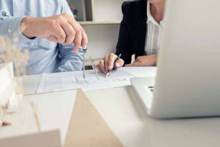 Engineering or Creative architect in construction project, Engineers hands working with compasses on construction blueprint building at a workplace in office, Building and architecture concept.の写真素材