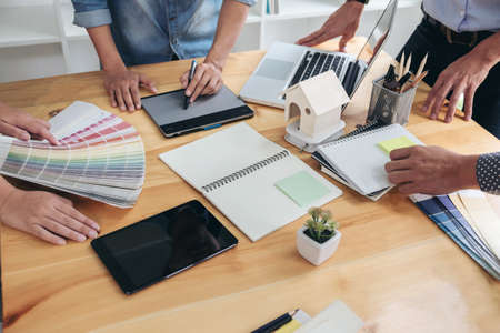 Young colleagues designers working together on a creative project and color samples for selection,...