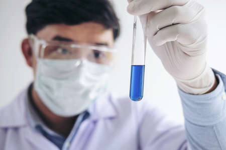 Scientist or medical in lab coat holding test tube with reagent, mixing reagents in glass flask in laboratory research.の写真素材