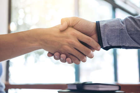 Two smiling businessman shaking hands together after good deal connection to join investment...