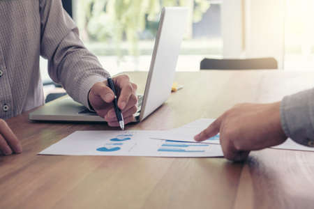 Business team two colleagues discussing new plan financial graph data on office table with laptop...