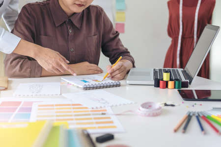 Two professional stylish fashion designer working as fashion designers measure as sketches in...