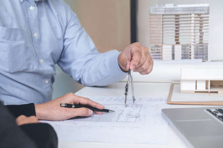 Engineering or Creative architect in construction project, Engineers hands working with compasses on construction blueprint building at a workplace in office, Building and architecture concept.の写真素材