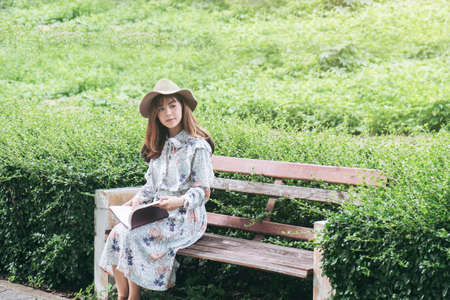 Attractive asian woman reading a book and relaxing at the park.の写真素材