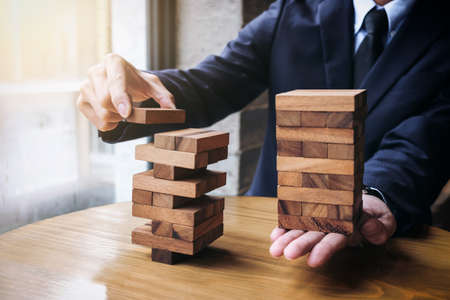 Alternative risk concept, plan and strategy in business, Young intelligent businessman playing the wood game, hands of executive cooperate placing wood block on the tower, Collaborative management.の写真素材