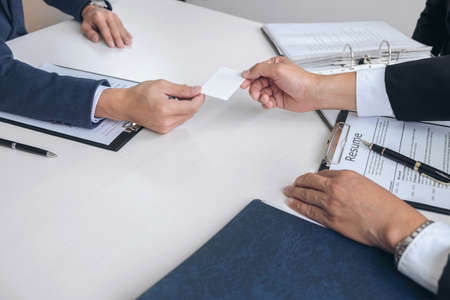 Interviewer or Board reading a resume during job interview, Employer interviewing a young male job seeker for recruitment talking in modern office and filing card, employment and recruitment concept.の写真素材
