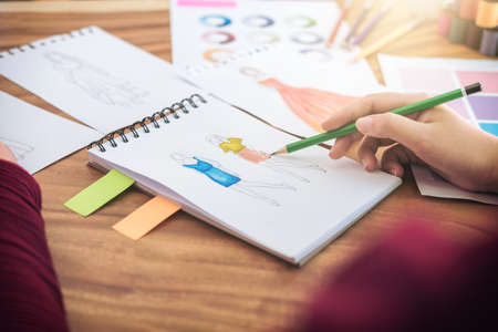 Close up of professional Fashion designer working and drawing sketches for clothes in workplace and color charts.の写真素材