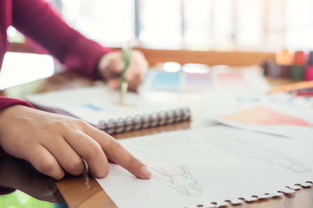 Close up of professional Fashion designer working and drawing sketches for clothes in workplace and color charts.の写真素材