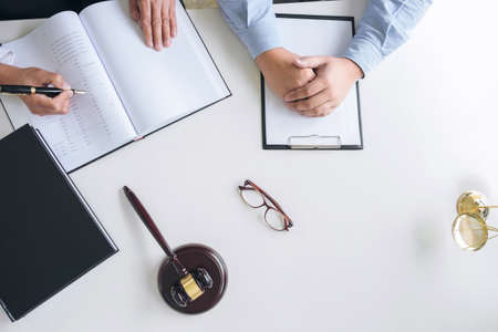 Close up of gavel, Male lawyer or judge Consult with client and working with Law books, report the case on table in modern office, Law and justice concept. Top view.の写真素材