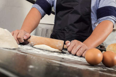 Male hands kneading dough sprinkled with flour table, Hands preparing bread, Raw dough for bread...