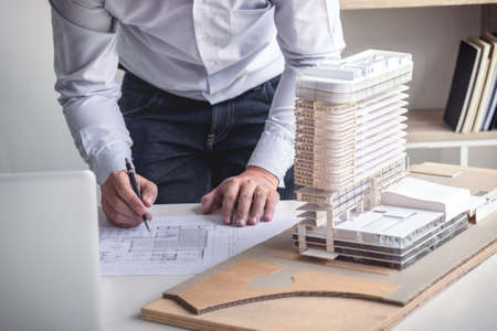 Engineering or Creative architect in construction project, Engineers hands working on construction blueprint and building model at a workplace in office, Building and architecture concept.の写真素材