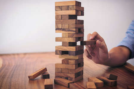 Images of hand of businesspeople placing and pulling wood block on the tower, Alternative risk concept, plan and strategy in business, Risk To Make Business Growth Concept With Wooden Blocks.の写真素材
