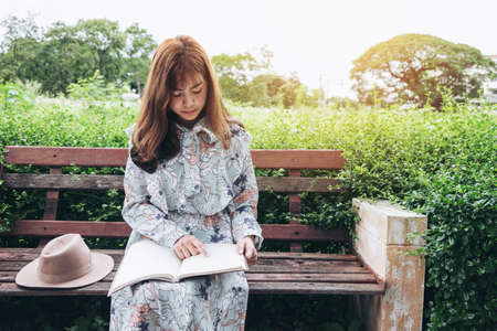 Attractive asian woman reading a book and relaxing at the park.の写真素材