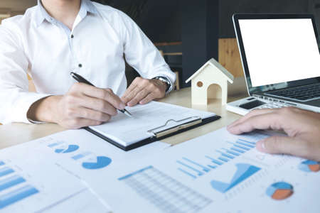 Man sign a home insurance policy on home loans, Agent holds loan and investment chart graph documents, table installment payment, Real Estate concept.の写真素材