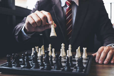 Close up of hands confident businessman colleagues playing chess game to development analysis new strategy plan, leader and teamwork concept for success.の写真素材