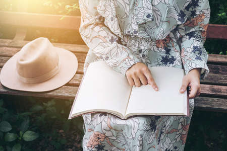 Attractive asian woman reading a book and relaxing at the park.の写真素材