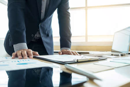 business man working and pointing to graph document finance project plan with laptop in home office. business concept.の写真素材