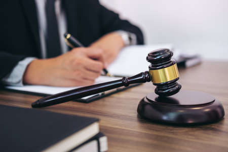 Gavel on wooden table and Lawyer or Judge working with agreement in Courtroom theme, Justice and Law concept.の写真素材