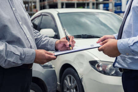Insurance Agent examine Damaged Car and customer filing signature on Report Claim Form process after accident, Traffic Accident and insurance concept.の写真素材