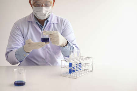 Scientist or medical in lab coat holding test tube with reagent, mixing reagents in glass flask in...