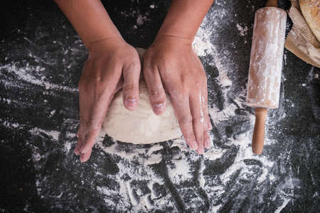 Male hands kneading dough sprinkled with flour table, Hands preparing bread, Raw dough for bread...