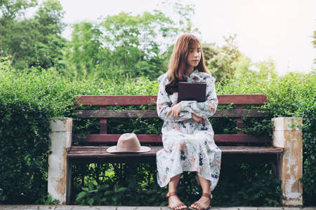 Attractive asian woman reading a book and relaxing at the park.の写真素材