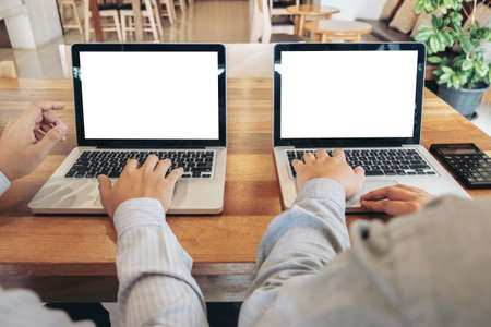Two business persons working at office desk and discussing using laptop to ideas of project about...