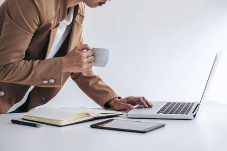 Young Entrepreneur woman manager working indoors at a modern office, typing and holding a coffee cup...