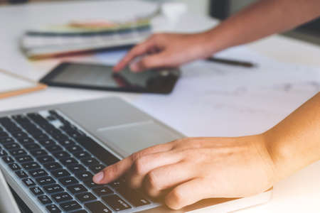 Two young women interior design or graphic designer working on project of architecture drawing with work tools and color swatches, colour chart in digital tablet at workplace.の写真素材